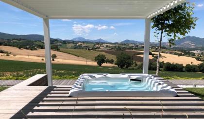 Vasca idromassaggio con vista su colline verdi e cielo azzurro.